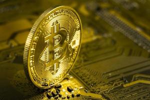 Makroansicht von goldfarbenen, glänzenden Münzen mit Bitcoin-Symbol auf einem Mainboard. foto