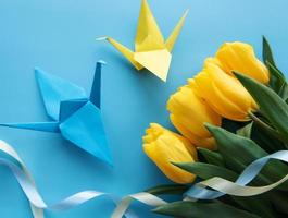 gelbe tulpen und origami-papiervögel auf blauem hintergrund