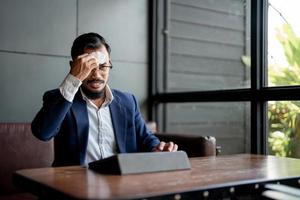 Geschäftsmann schaut auf seinen Laptop und wischt Schweiß mit Seidenpapier ab. foto