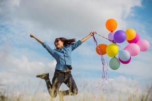 schönes Mädchen, das mit Luftballons am Strand springt foto