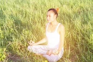 yoga in der stadt schöne junge fitte frau, die sportkleidung trägt, meditiert, atmet, sitzt mit gekreuzten beinen in halber lotushaltung auf der straße am sommertag, ardha padmasana, kopierraum foto