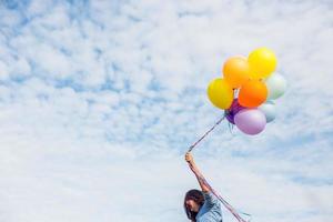 schönes Mädchen, das mit Luftballons am Strand springt foto