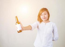 Fröhliches, charmantes Fitness-Mädchen in rosafarbener Spitze, das eine Flasche Wasser auf weißem Hintergrund zeigt foto