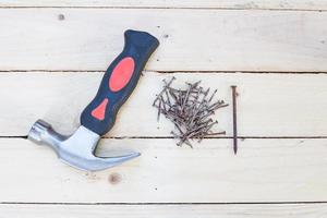 Hammer und rostige Nägel auf weißem Holzhintergrund foto