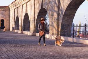 Junge Frau mit Hut im Park spazieren mit süßem Corgi-Hund, sonniger Herbsttag foto