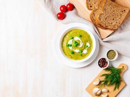 große weiße schüssel mit gemüsegrüner cremesuppe aus brokkoli, zucchini, grünen erbsen foto