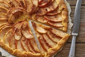 apfelkuchen, galette mit früchten, süßes gebäck auf altem rustikalem holztisch. Teil des Kuchens, Nahaufnahme foto