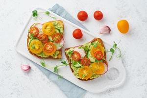 Avocado-Toast mit Kirschtomaten und Kräutern, Frühstück, Draufsicht foto