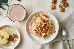 haferflocken mit apfel, nüssen, honig und tasse schokolade auf weißem hölzernem hellem hintergrund. Ansicht von oben. gesundes ernährungsfrühstück foto