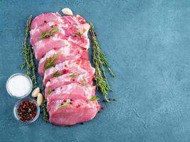 Schweinesteak, rohes Karbonatfilet auf dunklem Hintergrund, Fleisch mit Gewürzen, Draufsicht, Kopierraum foto