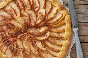 apfelkuchen, galette mit früchten, süßes gebäck auf altem rustikalem holztisch. Nahansicht foto