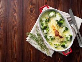 Hähnchenfilet gebacken mit Brokkoli in Bechamelsauce auf Holztisch. Gesundes Essen, sauberes Essen