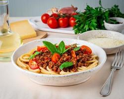 Pasta Bolognese mit Tomatensauce, Rinderhackfleisch, Basilikumblätter im Hintergrund