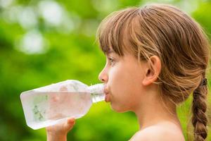 Kind trinkt sauberes Leitungswasser aus transparenter Plastikflasche