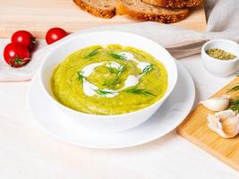 große weiße schüssel mit gemüsegrüner cremesuppe aus brokkoli, zucchini, grünen erbsen foto