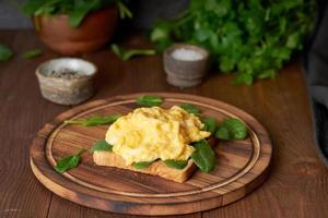 Toast mit Rührei und Spinat. Omelette. frühstück mit gebratenen eiern auf braun. foto