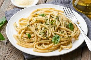 Pesto-Spaghetti-Nudeln mit Basilikum, Knoblauch, Pinienkernen, Olivenöl. rustikaler Tisch, Seitenansicht