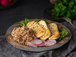 Halloumi, gegrillter Käse mit Quinoa, Salat, Rettich. ausgewogene Ernährung auf dunklem Hintergrund, Seitenansicht