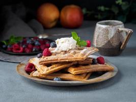 Belgische Waffeln mit Himbeeren, Schokoladensirup. Frühstück mit Tee auf dunklem Hintergrund, Seitenansicht foto