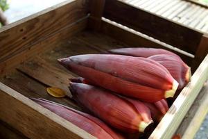 Bananenblütenhaufen in dunkelbrauner Holzkiste, Thailand. foto