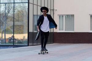 Konzept des jungen, schnellen und mobilen Managers. lustiger buisinessman auf skateboard im schwarzen anzug. foto