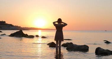 junge frau im kleid, das sich während des schönen sonnenaufgangs am sommerstrand entspannt foto