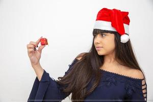 junge frau in der weihnachtsmütze, die weihnachtsgeschenk hält foto