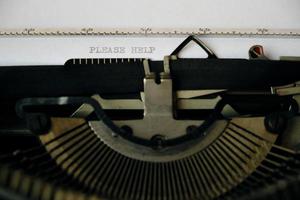 Inschrift bitte helfen wird mit einer alten Schreibmaschine auf ein weißes Blatt gedruckt. foto