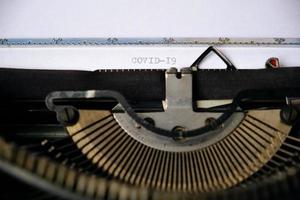 die aufschrift covid-19 ist mit einer alten schreibmaschine auf ein weißes blatt gedruckt.