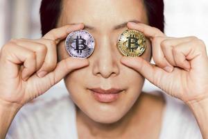 Frau, die Bitcoin vor ihren Augen hält. Online-Konzept für virtuelle zukünftige Währungen.