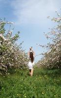 junge kaukasische frau, die die blüte eines apfelbaums genießt foto