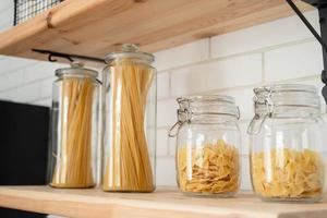 Italienische Weizennudeln im Glas auf einem Holzregal in der Küche. foto