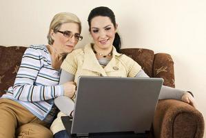 lächelnd zwei frauen mit laptop nach hause foto