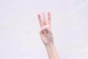 Hand der jungen Frau zeigt drei Finger auf dem isolierten weißen Hintergrund. foto