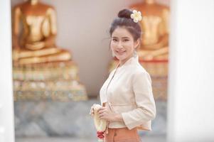 schöne thailändische frauen in traditioneller thailändischer kleidung verwenden frische blumengirlanden, um dem buddha-bild zu huldigen, um sich auf dem thailändischen songkran-fest etwas zu wünschen foto