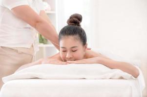 eine schöne asiatische frau ist angenehm entspannt und schläft in einem spa-shop, nachdem die masseurin ihren körper massiert hat
