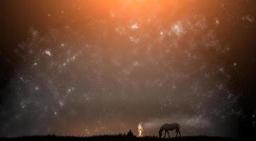 Silhouette eines Mannes und eines Pferdes vor dem Hintergrund des Sternenhimmels foto