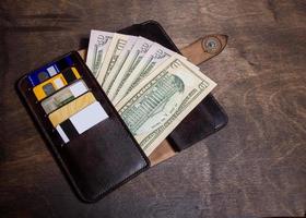 Ledergeldbörse mit Geld und Karten, die auf dem Tisch liegen foto