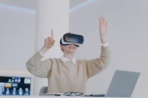 europäisches mädchen im vr-headset klicken sie auf schaltflächen in der virtuellen realität. Arbeit an einem Projekt für visuelle Effekte. foto