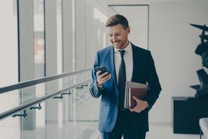 glücklicher gutaussehender mann ceo executive, der handy hält und während der kaffeepause im büro lächelt foto