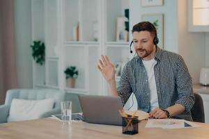 lächelnder junger mann, der zu hause mit laptop arbeitet foto