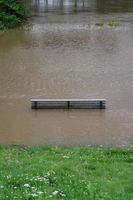 Flusshochwasser mit überfluteter Parkbank foto