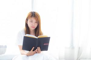 schöne junge asiatische frau des porträts entspannen sich beim lesen eines buches im schlafzimmer zu hause, mädchen studieren literatur, bildung und llifestyle-konzept. foto