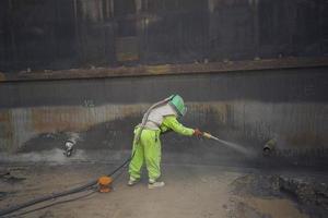 Oberflächenkorrosionsplattenvorbereitung der Arbeiterin durch Sandstrahlen foto