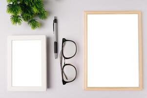 weißer fotorahmen, weiße tafel, stift, brille und blattzweige auf weißem hintergrund foto