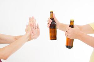 weibliche Hand lehnt eine Flasche Bier isoliert auf weißem Hintergrund ab. Anti-Alkohol-Konzept. Platz kopieren foto