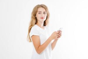 junge schöne Frau im T-Shirt mit ihrem Smartphone auf weißem Hintergrund. sexy blondes Mädchen im Chat mit Freund oder Online-Shopping. Platz kopieren foto