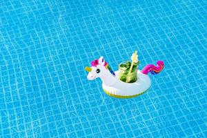 frischer coctail mojito auf aufblasbarem weißem einhornspielzeug am schwimmbad. Urlaubskonzept. foto