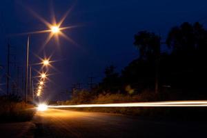 zünden Sie die Lampe mit den Scheinwerfern auf der Straße im Dunkeln an. foto