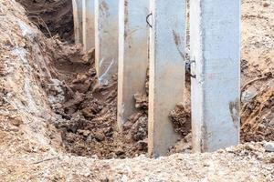 enge Betonpfeiler, die in einem ausgehobenen Graben installiert sind. foto